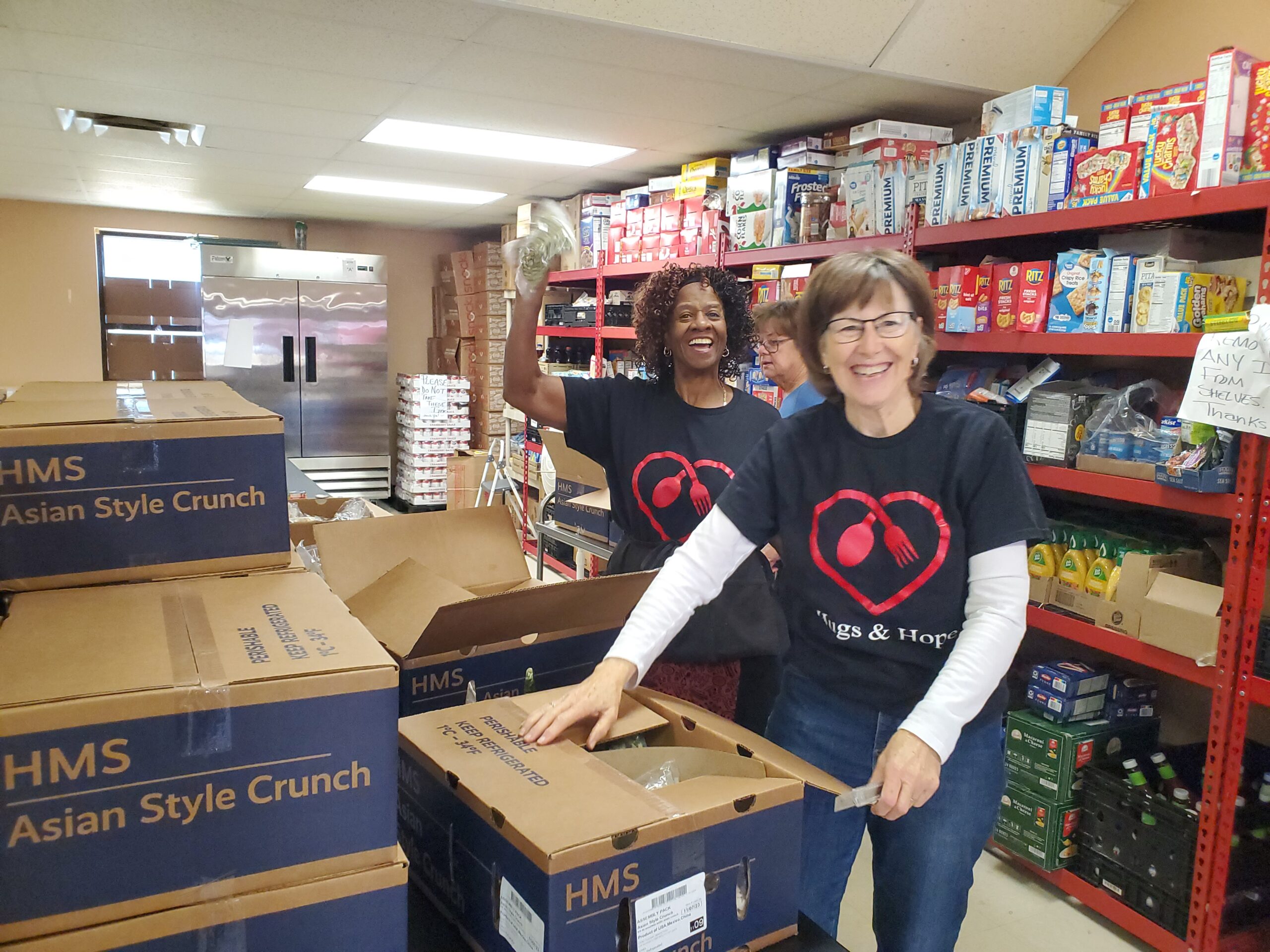 Two people standing in a warehouse next to boxes of food