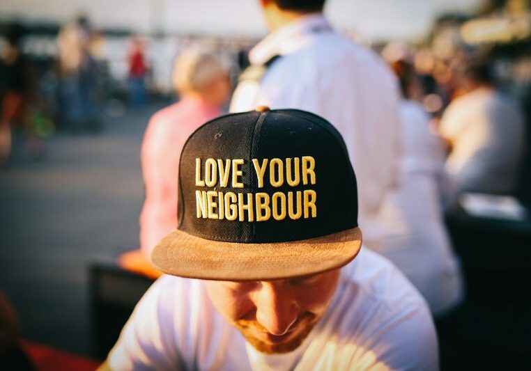 Image of a man wearing a cap with the words 'love your neighbour'